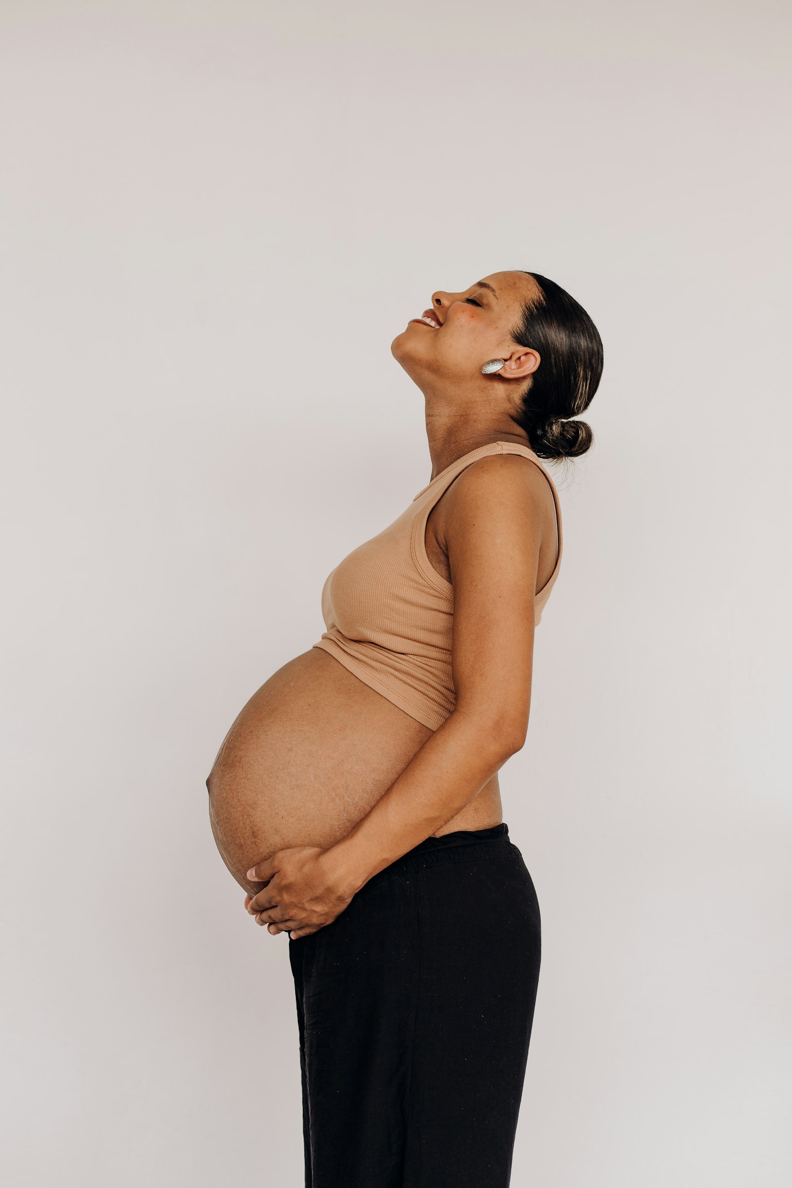 Pregnant woman gently holding her belly by a window